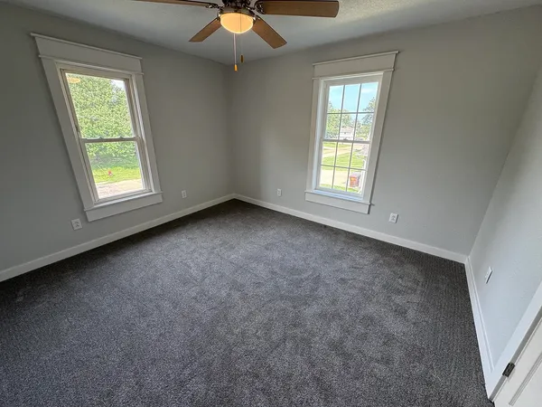 an empty room with windows and fan