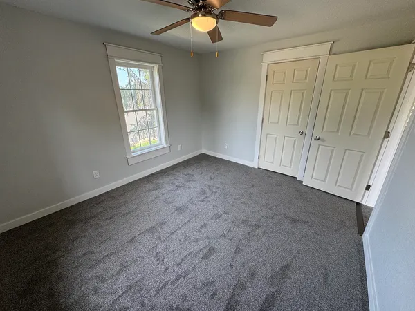 an empty room with a ceiling fan and a window