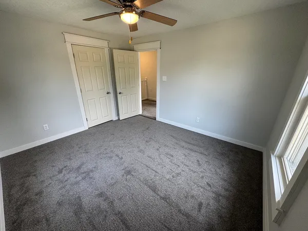 an empty room with windows and fan