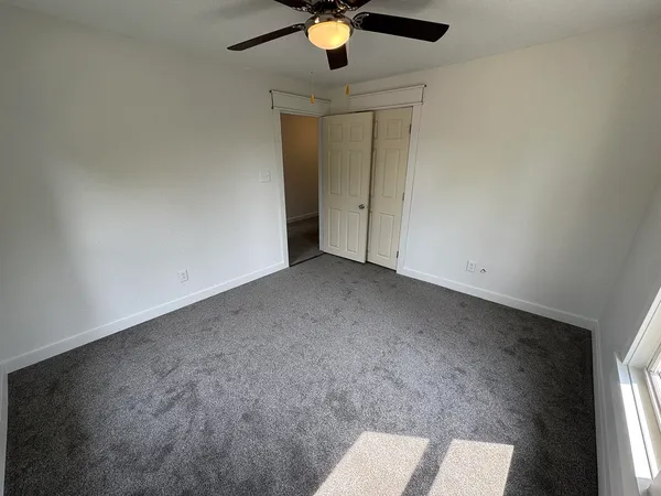 an empty room with windows and fan