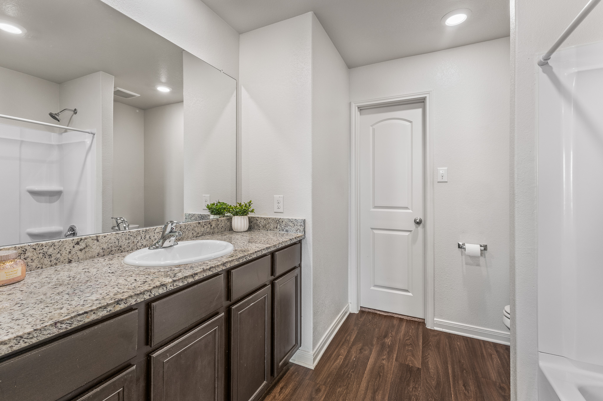 304 Hyacinth Way, Unit #7K Jarrell, TX 76537 - Photo 15 of 26 Functional bathroom featuring a shower, vanity with a large mirror, and durable wood flooring.