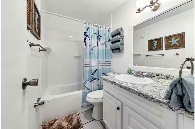 a bathroom with a granite countertop sink a toilet a mirror and shower