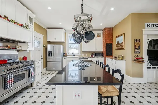 a kitchen with stainless steel appliances granite countertop a stove a refrigerator a sink dishwasher a dining table and chairs with wooden floor