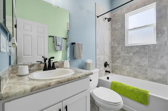 a bathroom with a granite countertop toilet a sink and a bathtub
