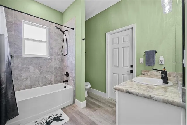 a bathroom with a granite countertop bathtub sink vanity mirror and toilet