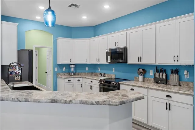 a kitchen with stainless steel appliances granite countertop a sink a stove a refrigerator and cabinets