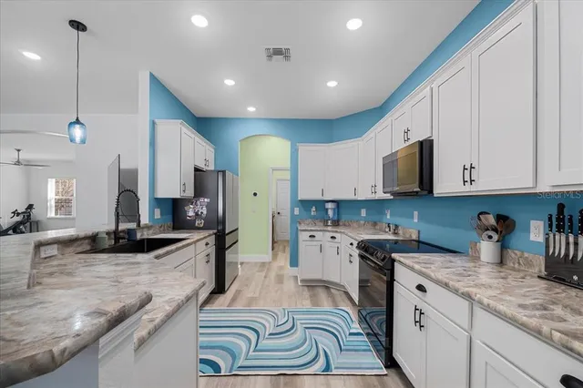 a kitchen with kitchen island granite countertop a sink a counter top space appliances and cabinets