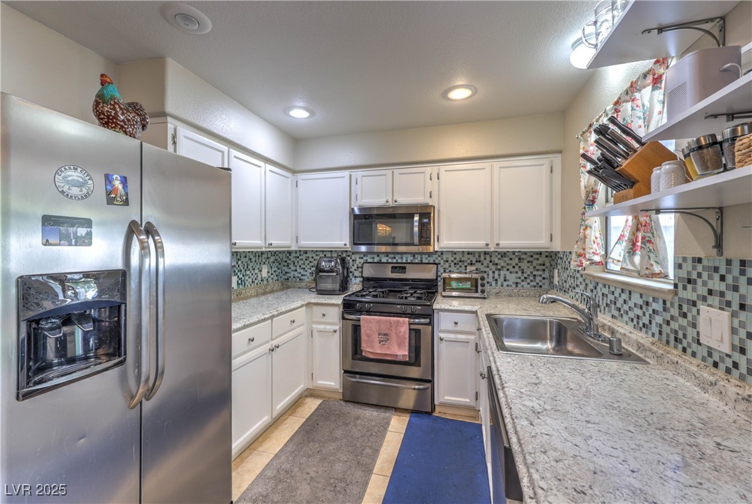 8056 Cimarron Ridge Drive, Unit 101 Las Vegas, NV 89128 - Photo 11 of 31 Kitchen with stainless steel appliances, white cabinetry, tasteful backsplash, open shelves, and recessed lighting