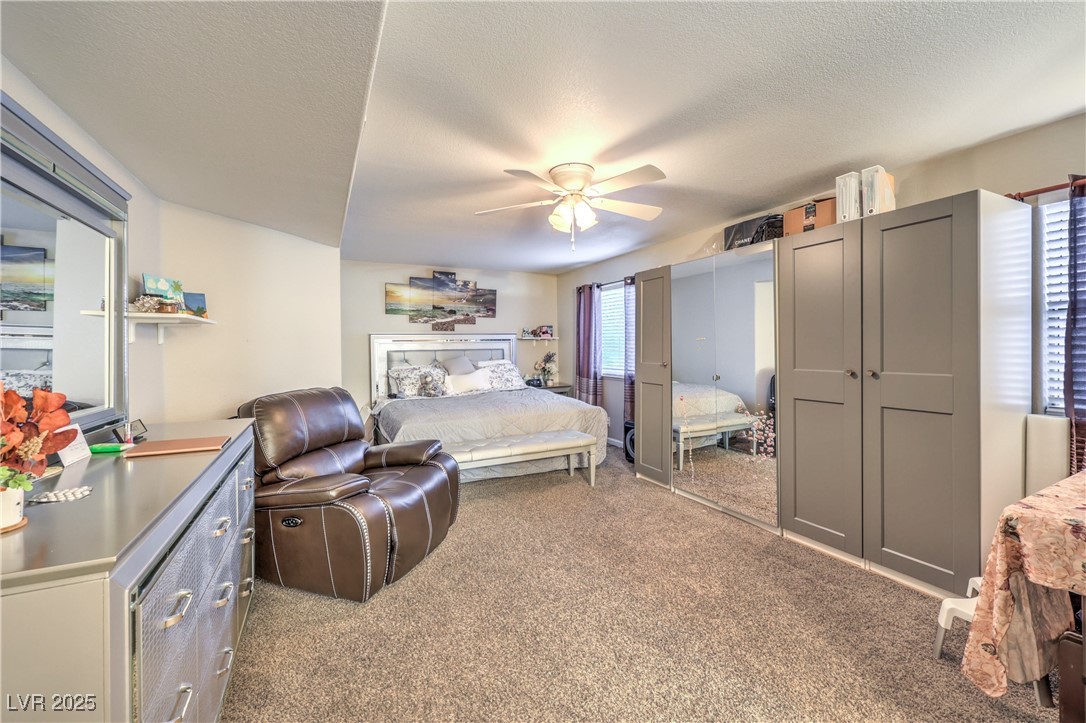 8056 Cimarron Ridge Drive, Unit 101 Las Vegas, NV 89128 - Photo 15 of 31 Bedroom featuring carpet, ceiling fan, and a textured ceiling