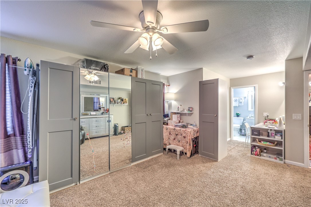 8056 Cimarron Ridge Drive, Unit 101 Las Vegas, NV 89128 - Photo 17 of 31 Bedroom with light colored carpet, a textured ceiling, ceiling fan, a closet, and connected bathroom