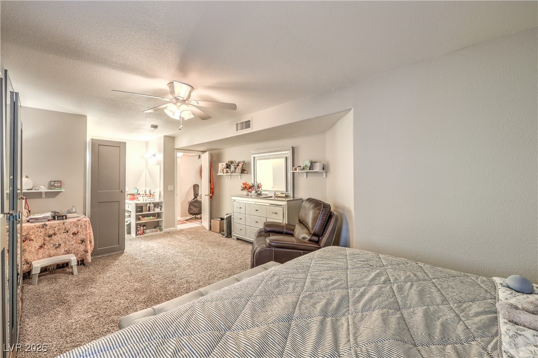 8056 Cimarron Ridge Drive, Unit 101 Las Vegas, NV 89128 - Photo 18 of 31 Carpeted bedroom featuring a ceiling fan and a textured ceiling