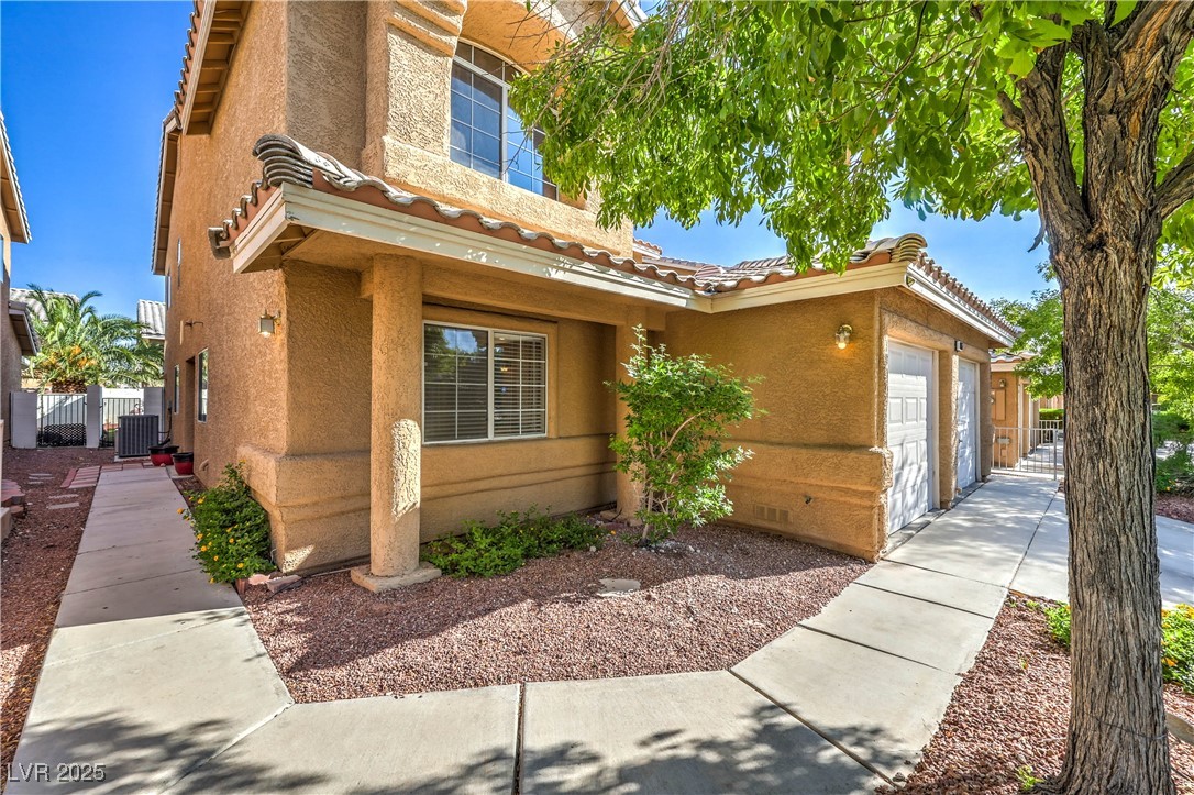 8056 Cimarron Ridge Drive, Unit 101 Las Vegas, NV 89128 - Photo 2 of 31 View of front facade with a tile roof, stucco siding, a gate, and an attached garage