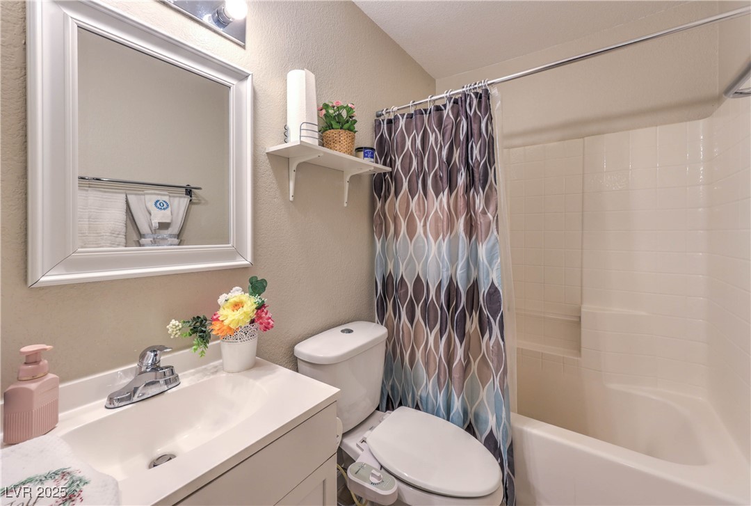 8056 Cimarron Ridge Drive, Unit 101 Las Vegas, NV 89128 - Photo 23 of 31 Full bathroom featuring a textured wall, vanity, and shower / tub combo with curtain