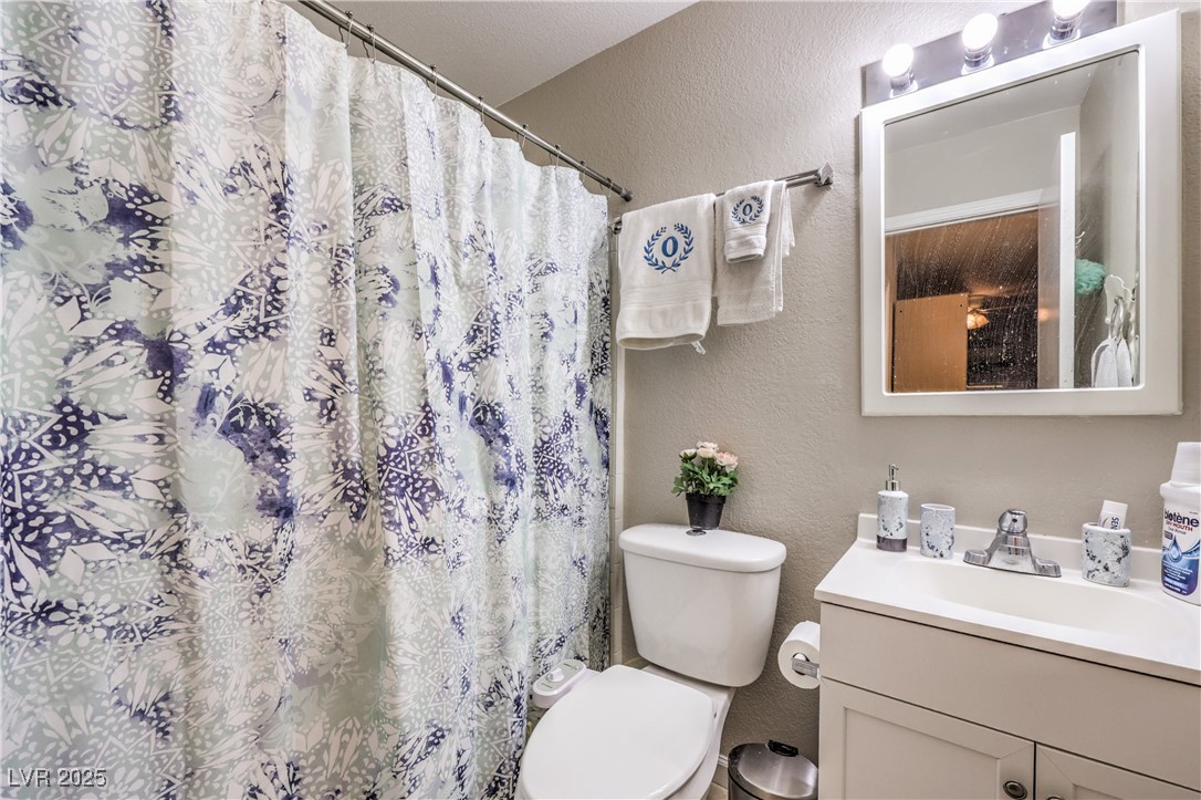 8056 Cimarron Ridge Drive, Unit 101 Las Vegas, NV 89128 - Photo 24 of 31 Full bath featuring a textured wall, vanity, and a shower with curtain