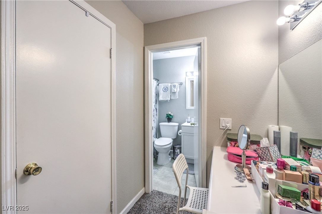 8056 Cimarron Ridge Drive, Unit 101 Las Vegas, NV 89128 - Photo 25 of 31 Bathroom with vanity, curtained shower, a textured wall, and light tile patterned flooring
