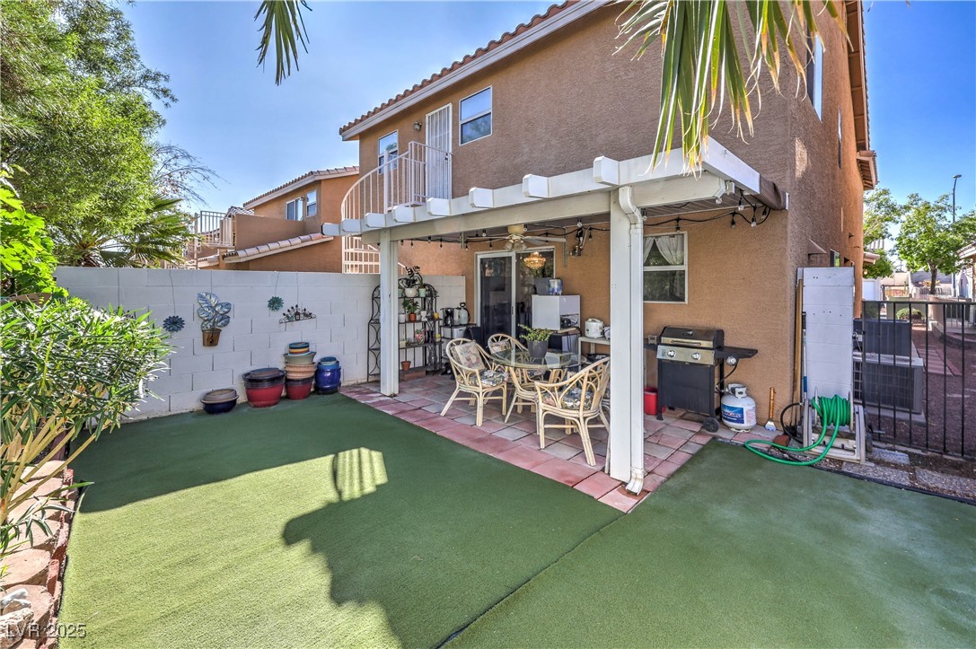8056 Cimarron Ridge Drive, Unit 101 Las Vegas, NV 89128 - Photo 30 of 31 Back of house with a fenced backyard, stucco siding, a patio, a balcony, and a tiled roof