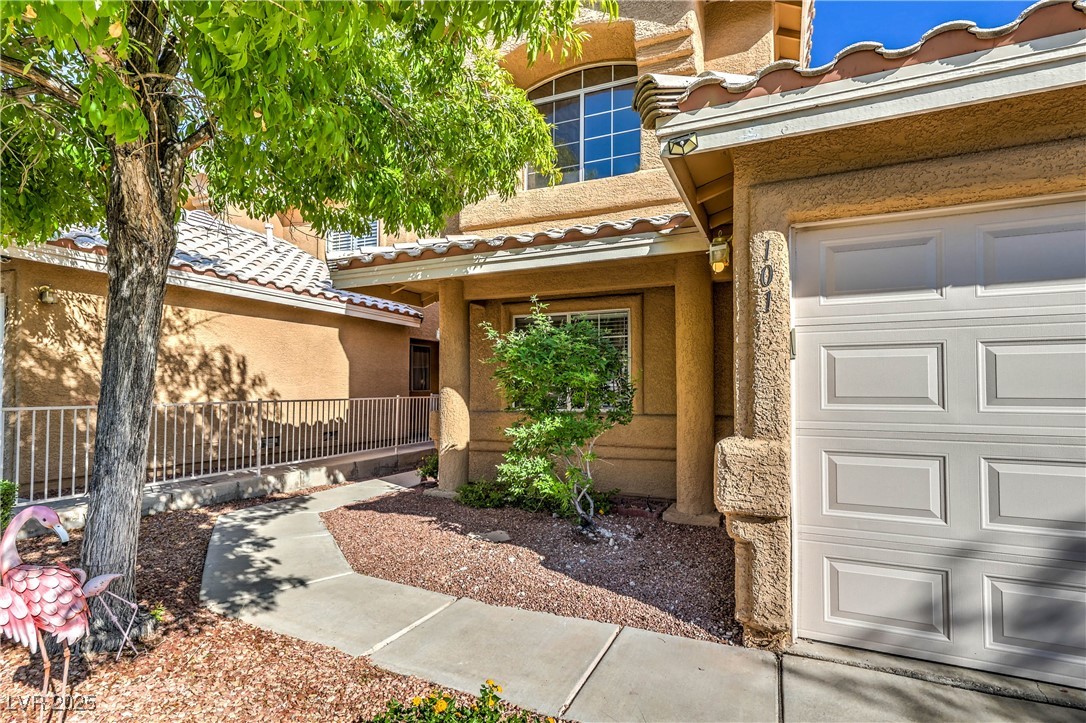 8056 Cimarron Ridge Drive, Unit 101 Las Vegas, NV 89128 - Photo 3 of 31 Doorway to property with stucco siding, a tile roof, and a garage