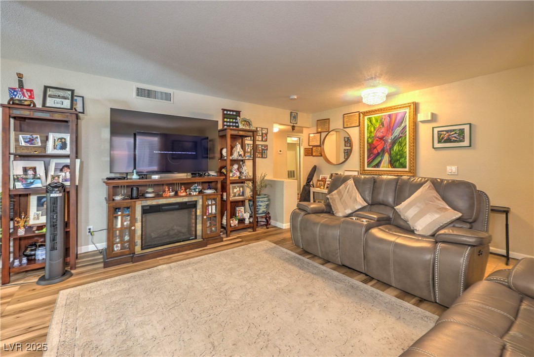 8056 Cimarron Ridge Drive, Unit 101 Las Vegas, NV 89128 - Photo 6 of 31 Living area with wood finished floors and a glass covered fireplace
