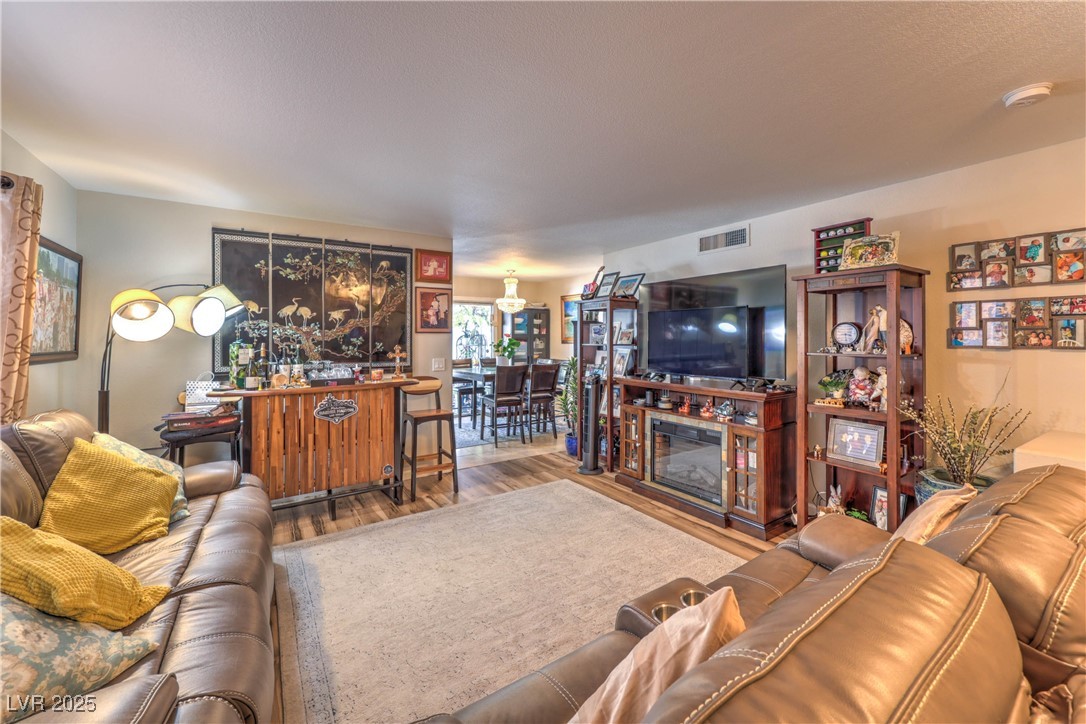 8056 Cimarron Ridge Drive, Unit 101 Las Vegas, NV 89128 - Photo 7 of 31 Living area with wood finished floors and a glass covered fireplace