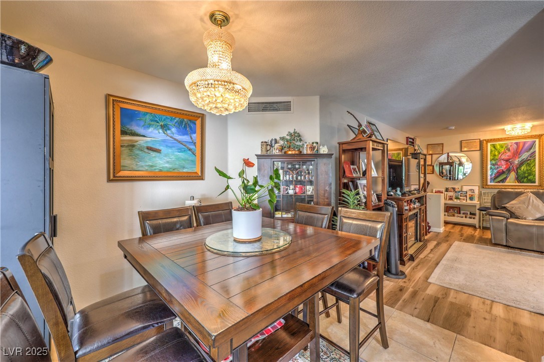 8056 Cimarron Ridge Drive, Unit 101 Las Vegas, NV 89128 - Photo 8 of 31 Dining area featuring a chandelier and wood finished floors