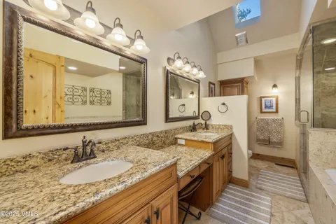 a spacious bathroom with a granite countertop double vanity sink a mirror and a shower