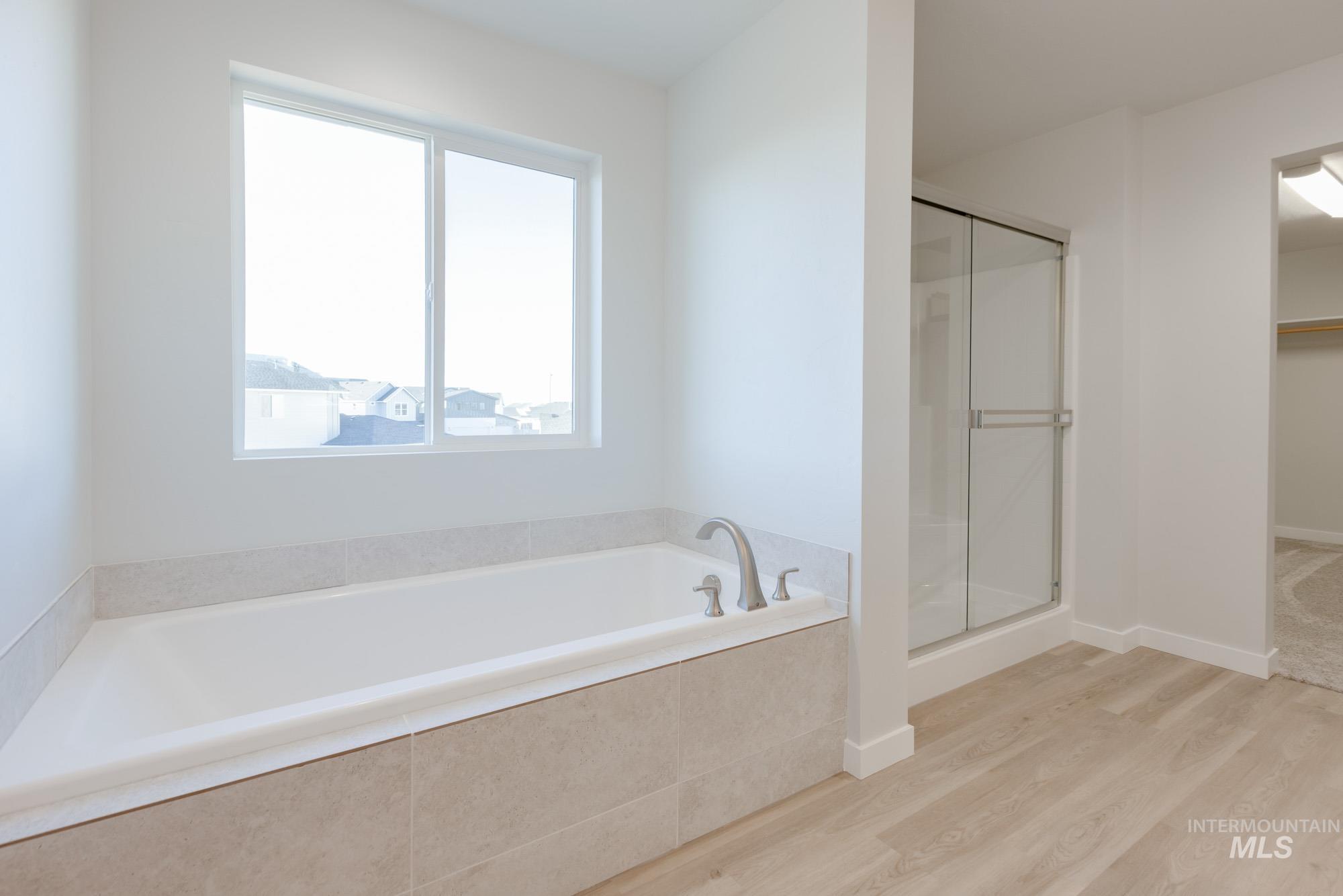 1639 Celina Street Middleton, ID 83644 - Photo 13 of 19 Soaking tub with brushed nickel fixtures, light-toned tile surround, and a clear window