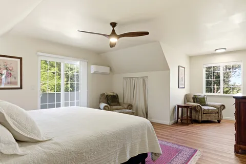 a bedroom with a bed wooden floor and windows