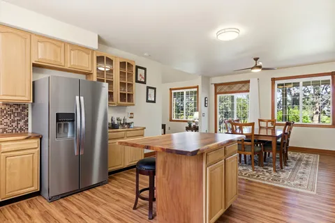 a kitchen with stainless steel appliances granite countertop a refrigerator a stove a sink dishwasher a dining table and chairs with wooden floor
