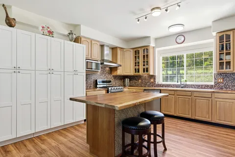 a kitchen with stainless steel appliances granite countertop a table chairs cabinets and wooden floor