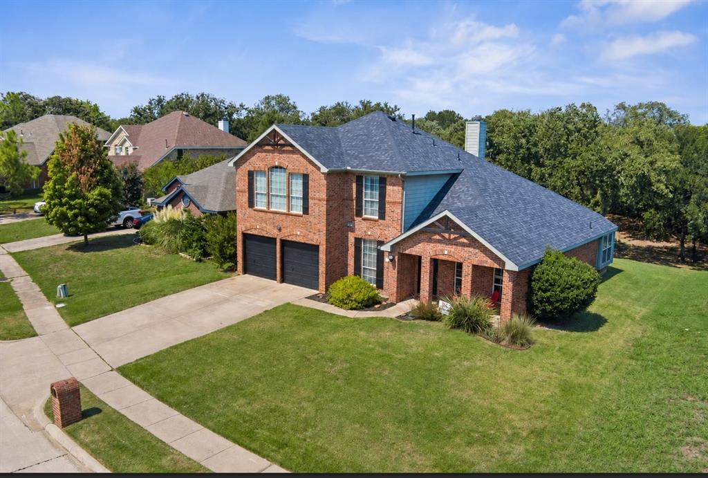 409 Springtree Road Lake Dallas, TX 75065 - Photo 3 of 40 Brick exterior with a dark shingle roof and a two-car garage