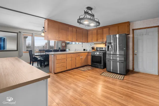 a kitchen with stainless steel appliances granite countertop a sink dishwasher stove and wooden cabinets with wooden floor