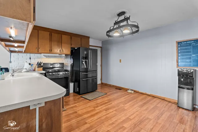 a kitchen with stainless steel appliances kitchen island granite countertop a refrigerator a stove and a sink with cabinets