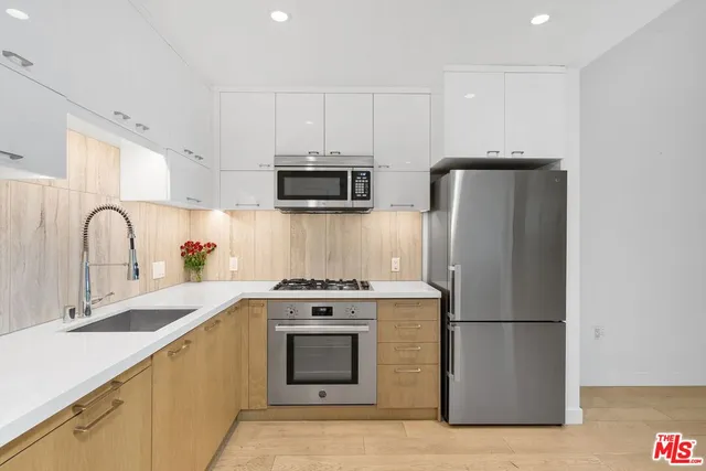 a kitchen with stainless steel appliances a refrigerator sink and white cabinets