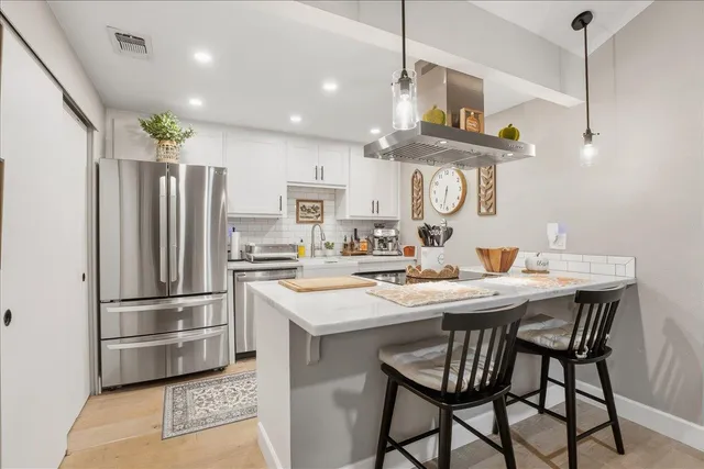a kitchen with stainless steel appliances a dining table chairs and wooden floor