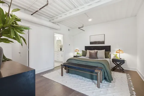 a bedroom with a bed table and a potted plant
