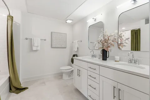 a spacious bathroom with 2 sink toilet and a mirror
