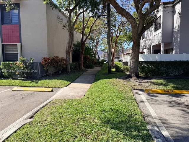 a front view of a house with a yard and palm trees