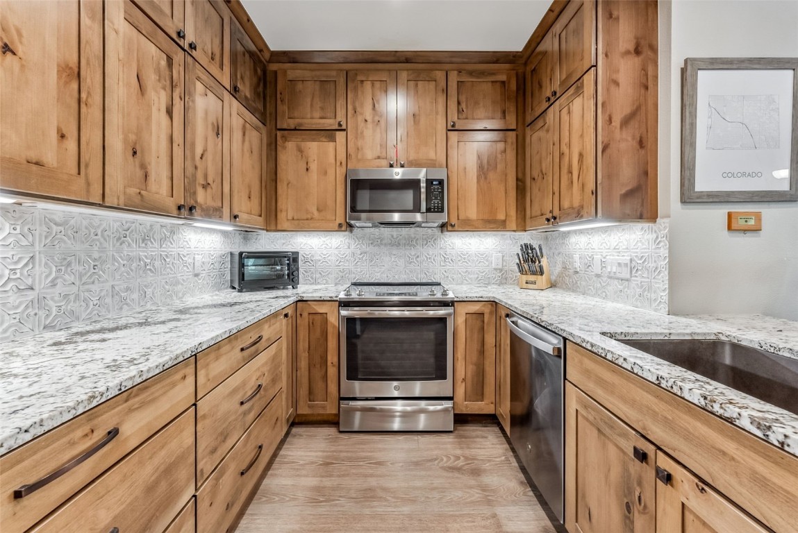 1203 West Keystone Road, Unit 2711 Keystone, CO 80435 - Photo 11 of 36 Kitchen featuring light stone counters, stainless steel appliances, tasteful backsplash, and light hardwood / wood-style flooring