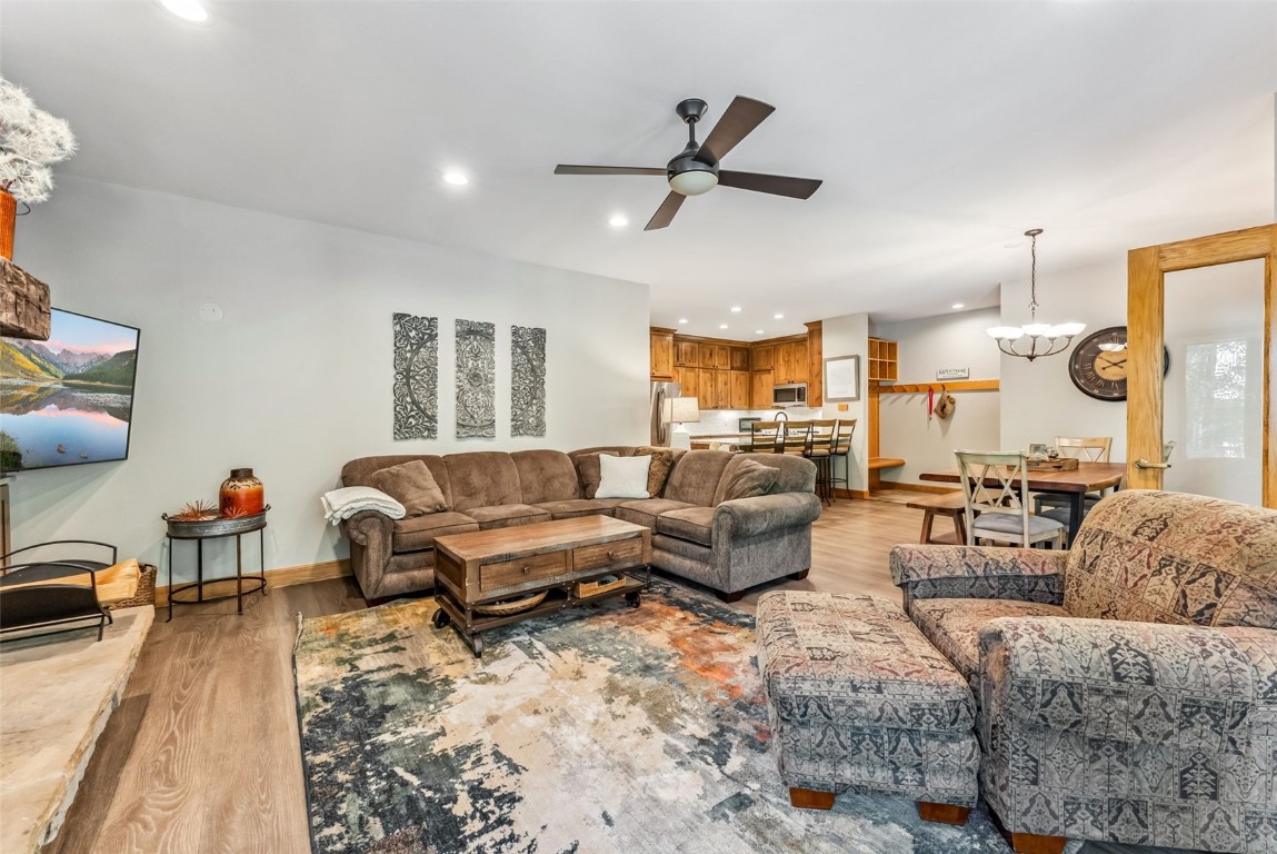 Living room with light hardwood / wood-style floors and ceiling fan with notable chandelier