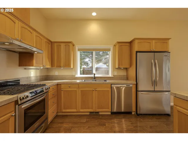 a kitchen with stainless steel appliances a refrigerator a sink a stove a microwave and white cabinets