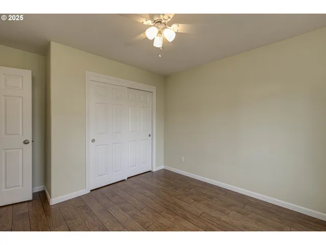a view of a room with a chandelier fan and wooden floor