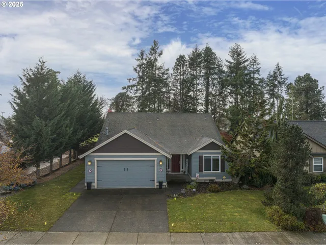 front view of house with a yard and trees all around