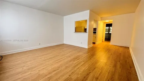 a view of a big room with wooden floor and windows