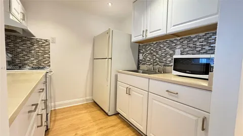 a kitchen with white cabinets and black appliances