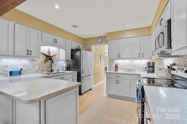 a kitchen with stainless steel appliances granite countertop a sink stove refrigerator and cabinets