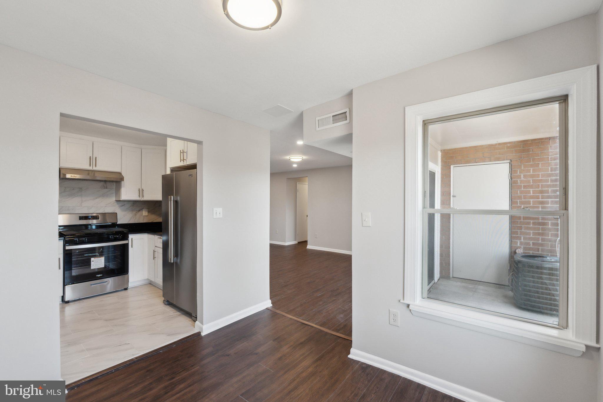 3809 St Barnabas Road, Unit T202 Suitland, MD 20746 - Photo 6 of 20 a view of a kitchen with a refrigerator a stove top oven and a hallway