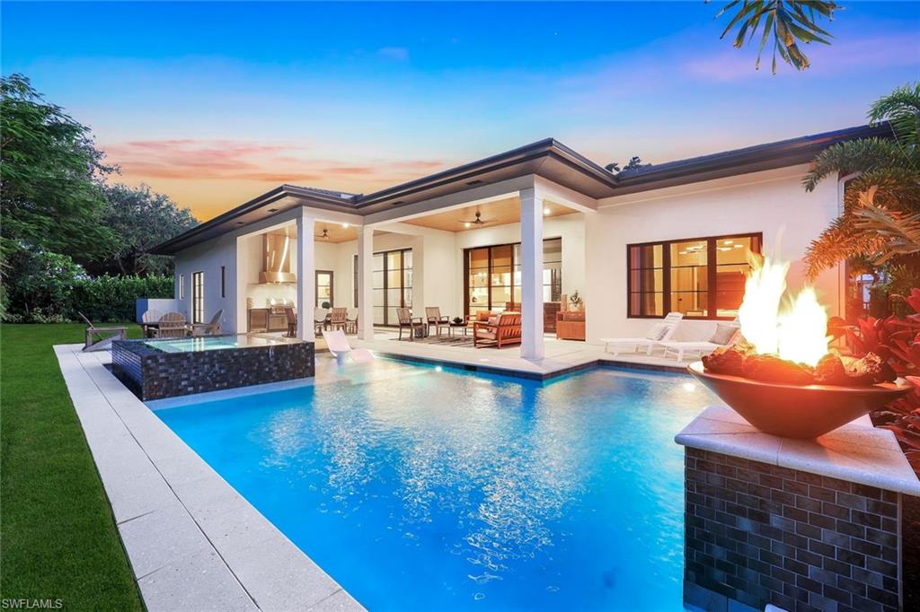 1546 Mandarin Road Naples, FL 34102 - Photo 1 of 48 Back of house at dusk featuring stucco siding, a patio, a ceiling fan, and an outdoor pool