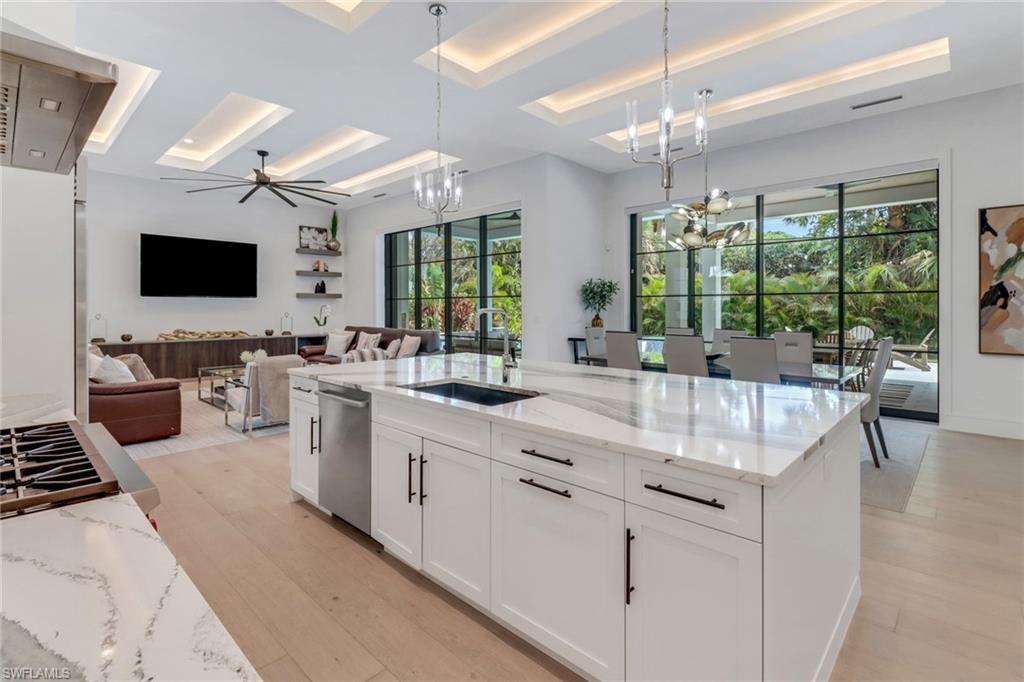 1546 Mandarin Road Naples, FL 34102 - Photo 15 of 48 Kitchen featuring a healthy amount of sunlight, light stone counters, sink, and pendant lighting