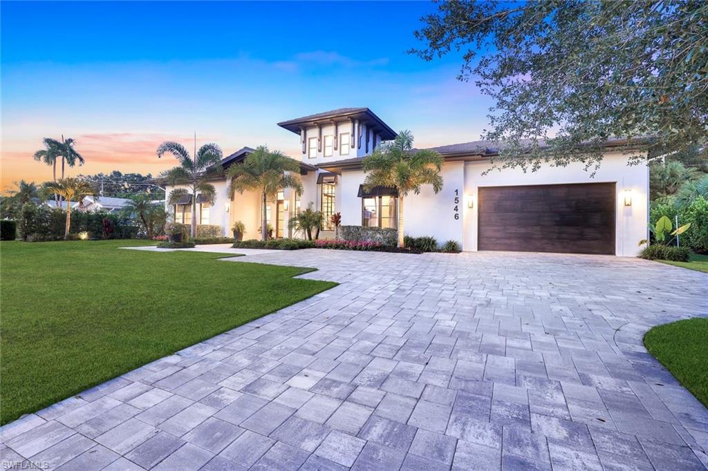 1546 Mandarin Road Naples, FL 34102 - Photo 2 of 48 Contemporary house with decorative driveway, a garage, stucco siding, and a lawn