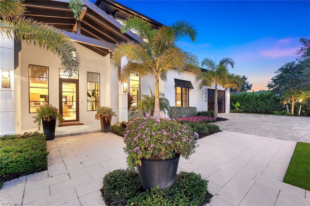 1546 Mandarin Road Naples, FL 34102 - Photo 4 of 48 Patio terrace at dusk featuring decorative driveway and an attached garage